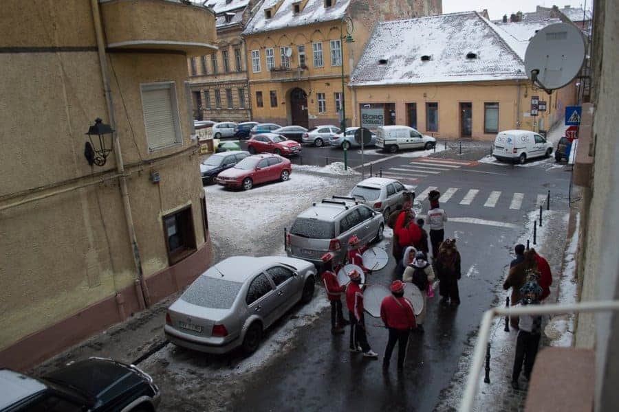 A marching band holds their instruments in a street covered in snow.