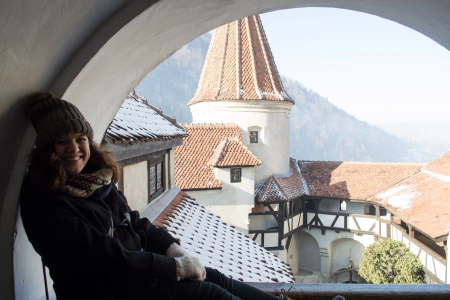 A woman smiles at a view of the tops of buildings dusted in snow.