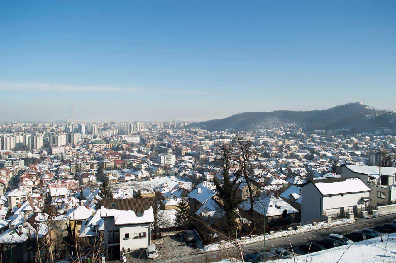 View of a city dusted by snow under a blue sky.