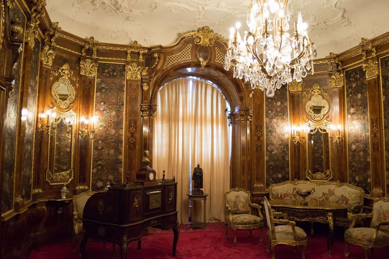 An elegant room with historic furniture and a dazzling chandelier hanging from the ceiling.