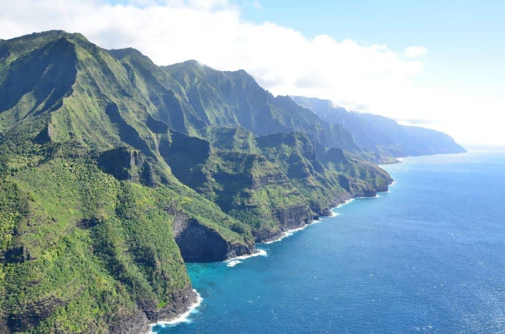 A large green mountain next to a blue body of water.