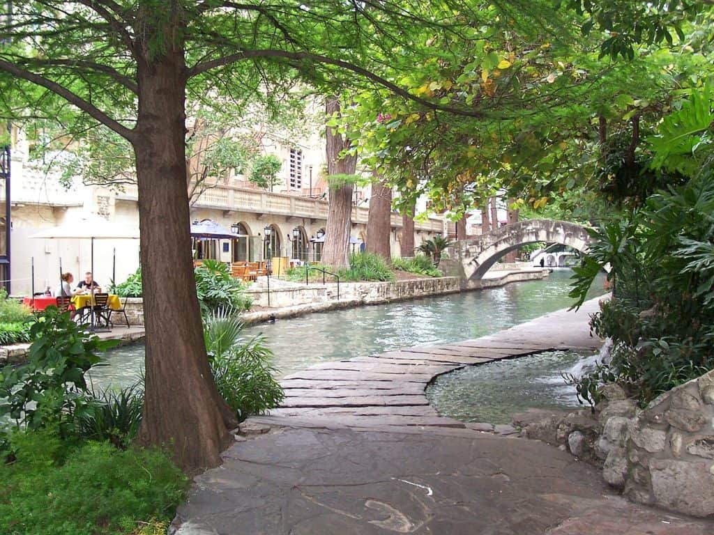 A walkway leads through the water. A bridge can be seen in the background.