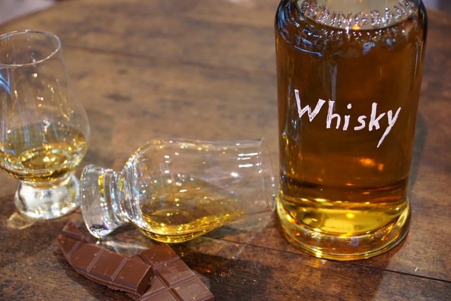 A cup of whiskey is spilled over next to chocolate.