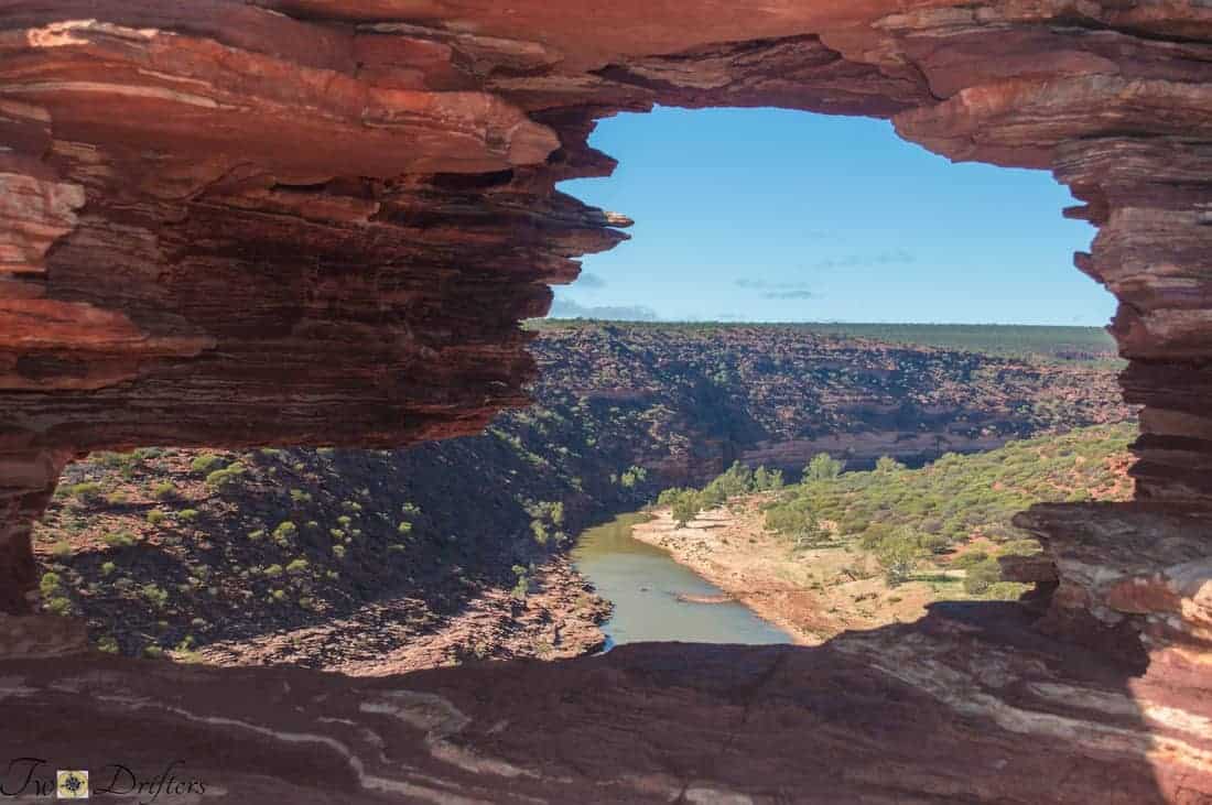 View of a canyon through red rocks with a river breaking through the middle of it