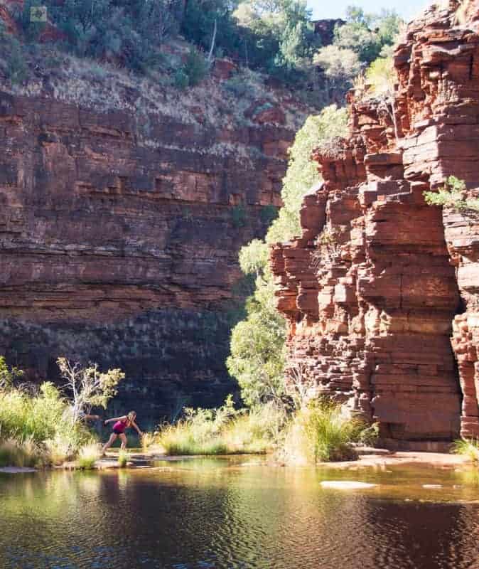 A person stands in the middle of a canyon surrounded by water