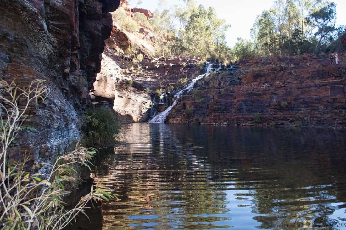 A waterfall trickles down rocks into a body of water