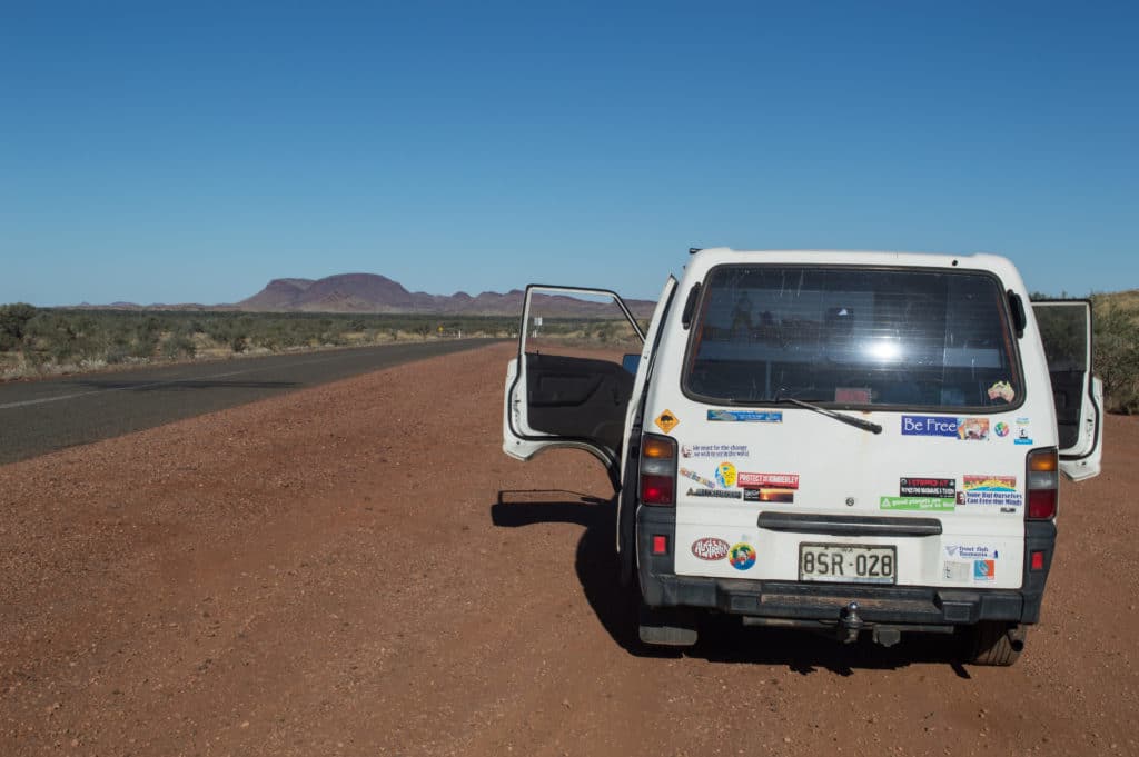 Back of a campervan with the front door open in the middle of a desert.