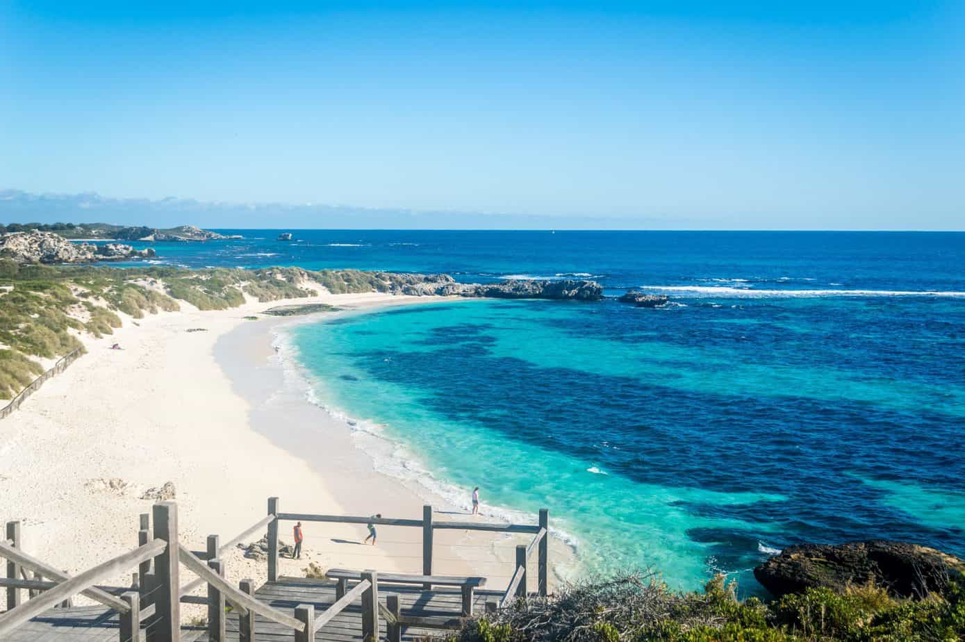 People walk around in the sand near blue waters.