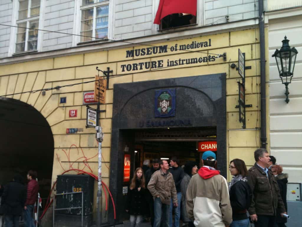 A group of people standing in front of a building that says Museum of Medieval Torture Instruments.