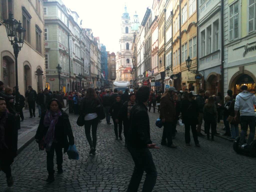 A group of people walking on a city street lined by buildings.