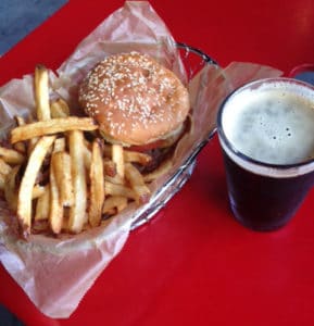 A basket of fries and a burger next to a soda.