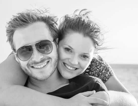 A woman has her arms around a man while they both smile.