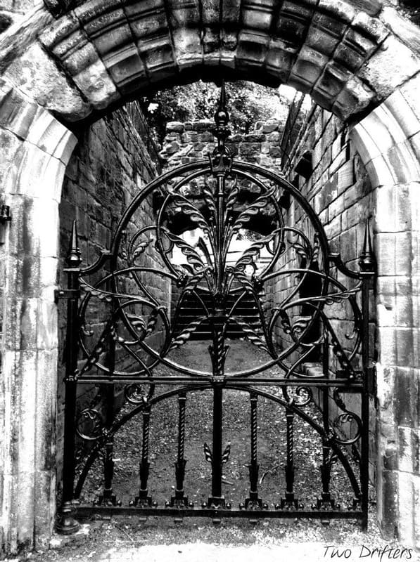 Wrought iron gate leading to a walkway in a black and white image.