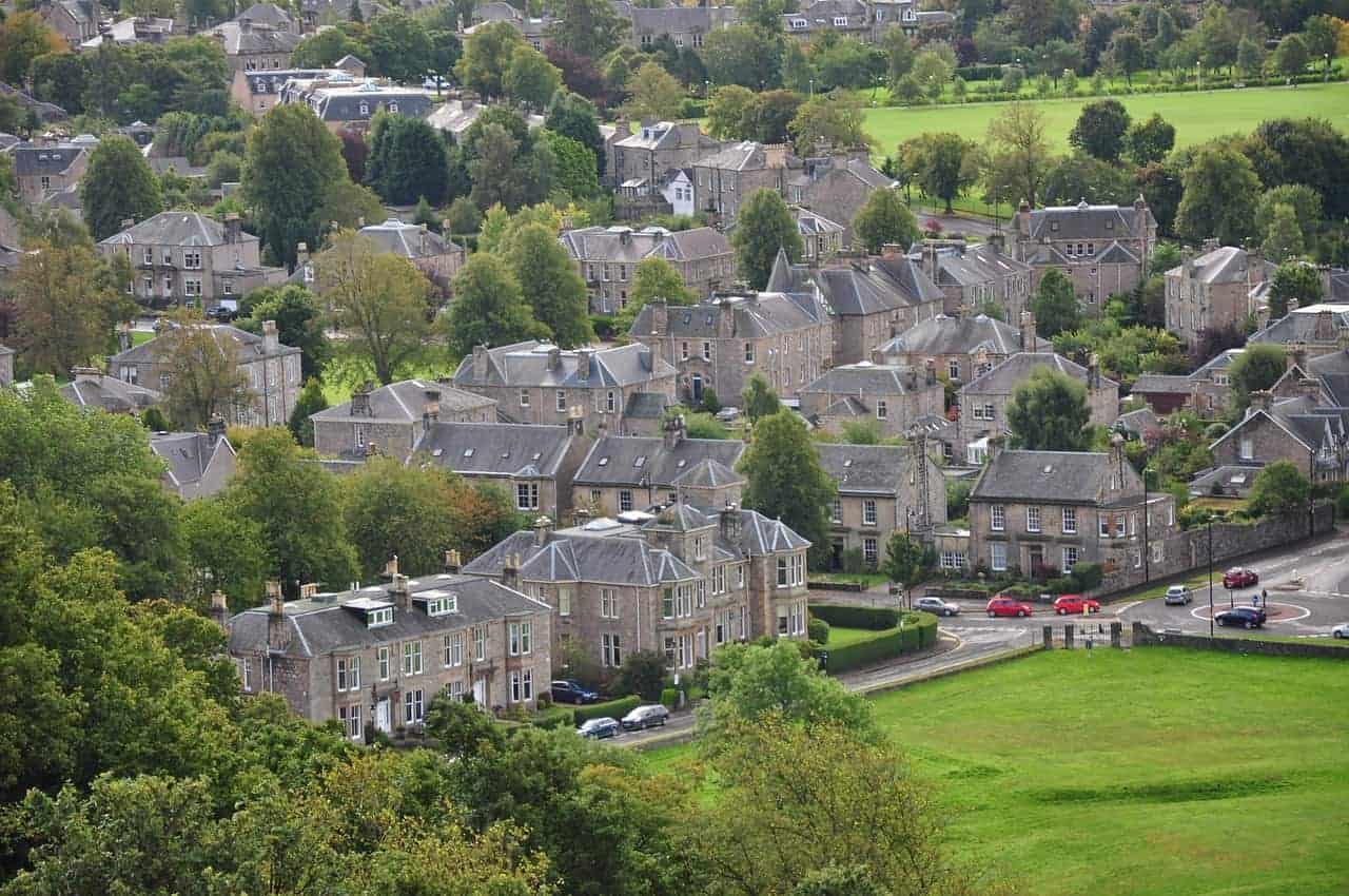 Aerial view of a town with stone buildings surrounded by greenery.