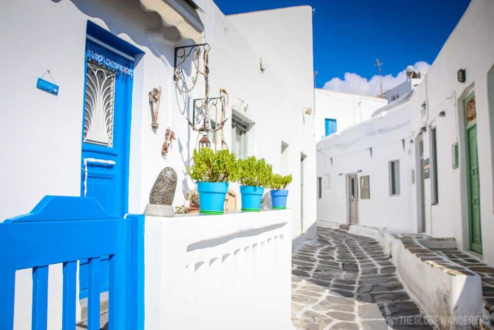 A cobblestone walkway leads between buildings of bright white with blue doors.