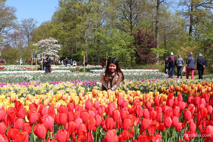 A girl smiles in a field filled with colorful tulips.