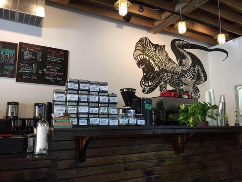 Inside of a coffee shop with a dinosaur drawn on the wall.