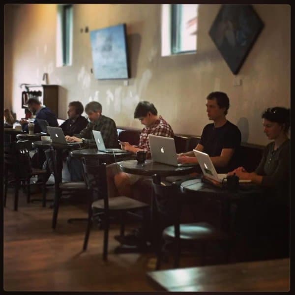 People sitting inside at a cafe while working on laptops.