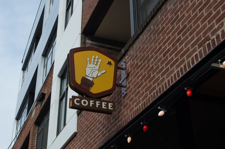 Yellow sign with a hand that says coffee underneath.