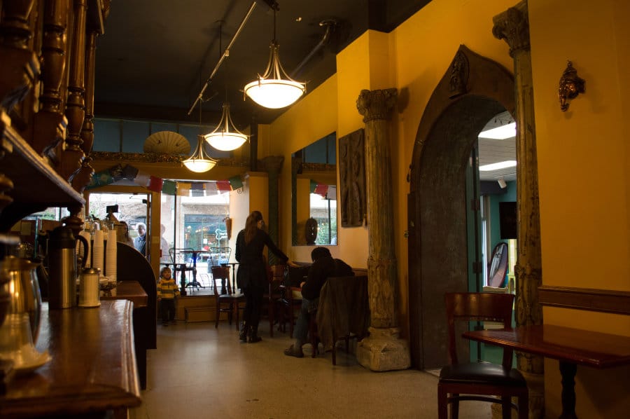 People chilling inside of a coffee shop with yellow walls.