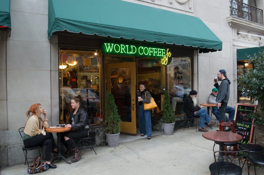 People sitting outside of a cafe that says World Coffee Cafe.