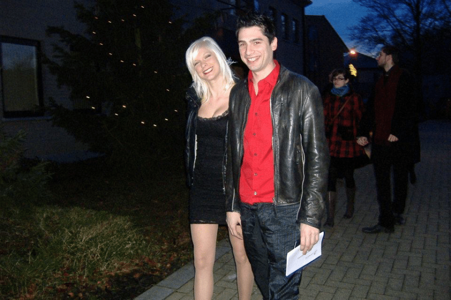 Man and woman walking on a street while smiling at night.