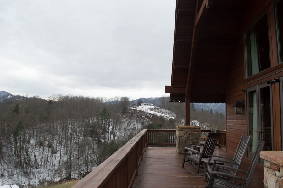 View of a snowy landscape from a wooden porch.