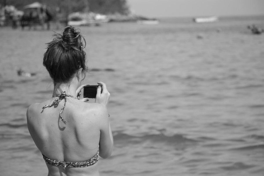 A woman with a camera takes a photo of the water.