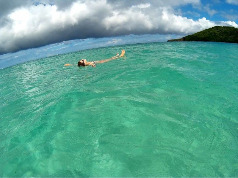 A person floats in green water.