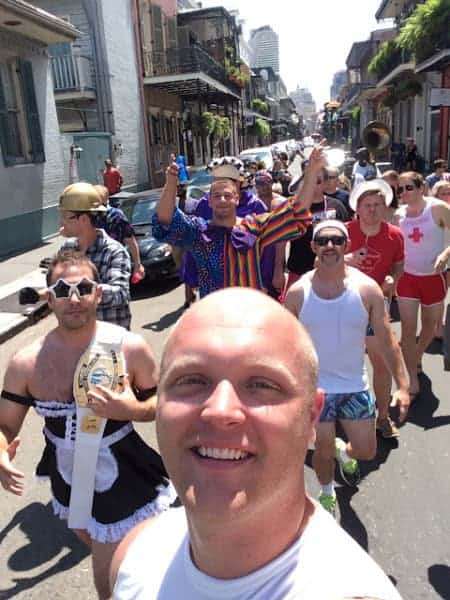 A group of people in a street smile with a street lined by shops.