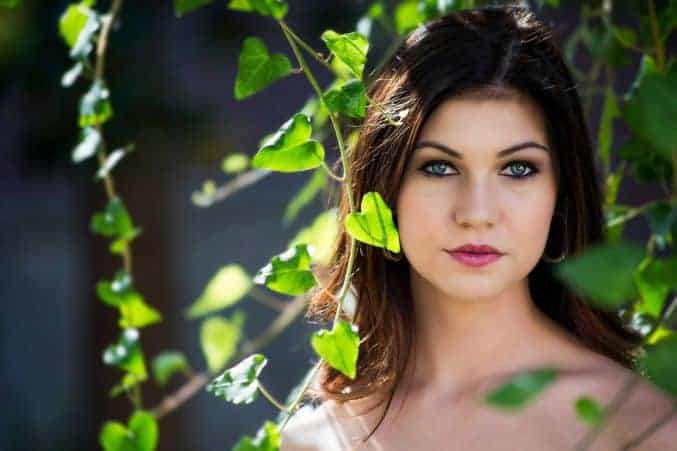 A woman poses next to plants.