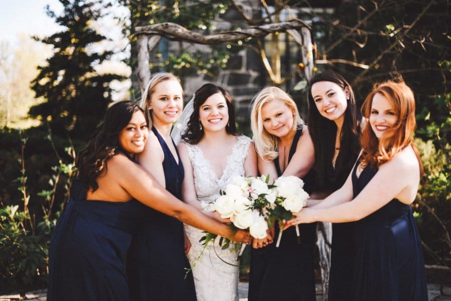 A woman in a wedding dress is surrounded by her bridesmaids.