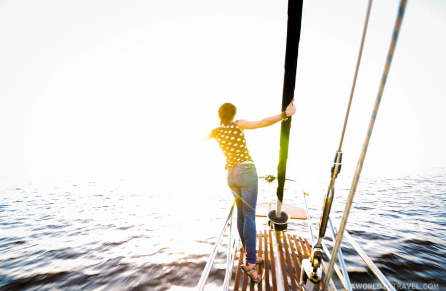 A woman holding onto a ship looking out to the water.