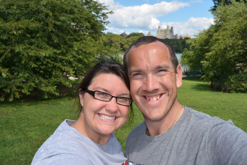 A couple smiles with a historic castle behind them.