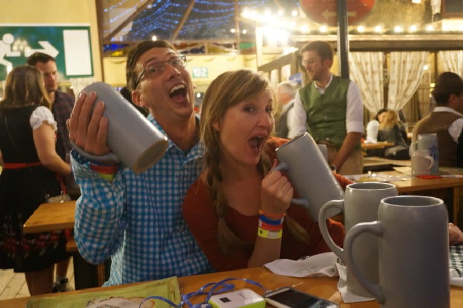 A couple smiles at a restaurant holding steins.