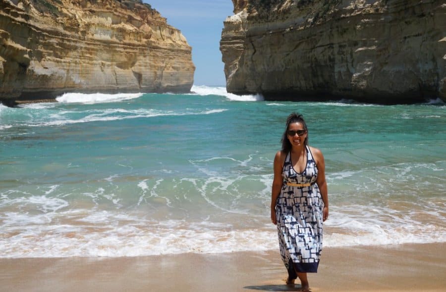 A woman in a blue dress smiles next to the ocean.