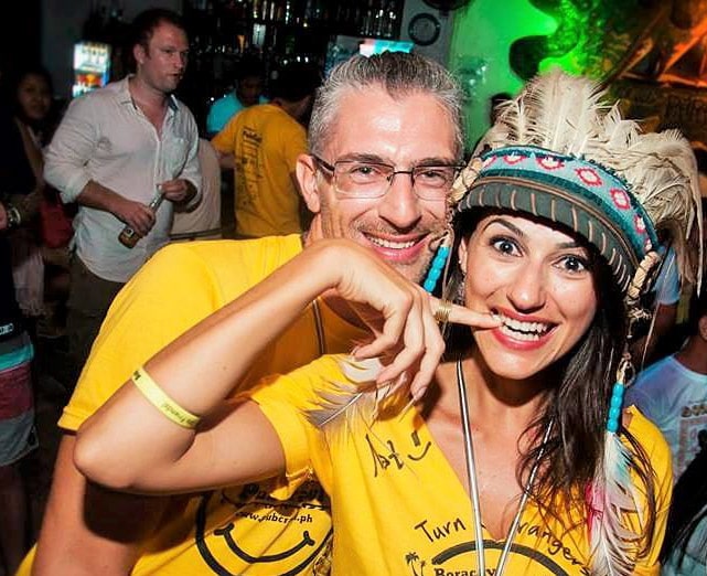 A couple smiles wearing matching yellow shirts.