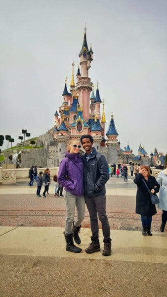 A couple smiles in front of the Disneyland castle.