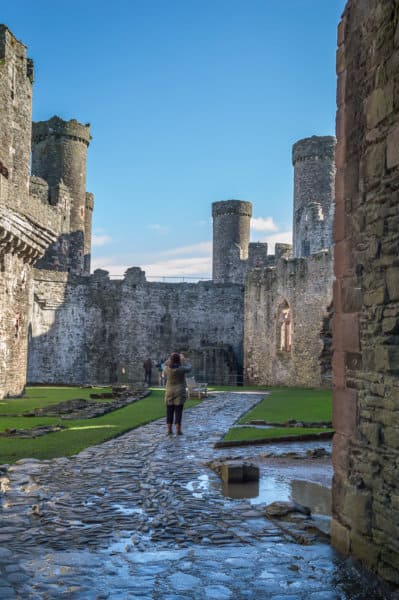 A woman takes a photo of inside a stone castle