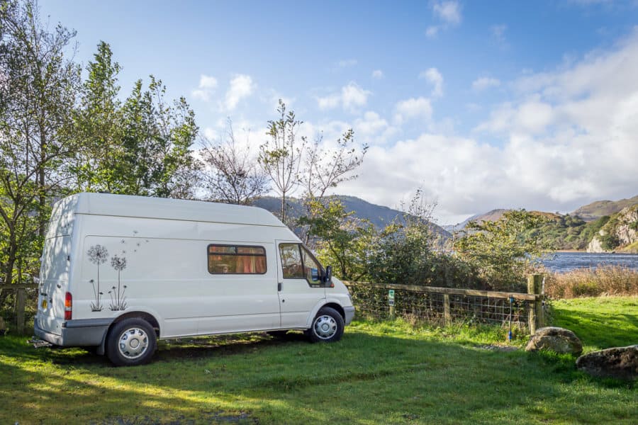 A van is parked on grass with mountains in the background