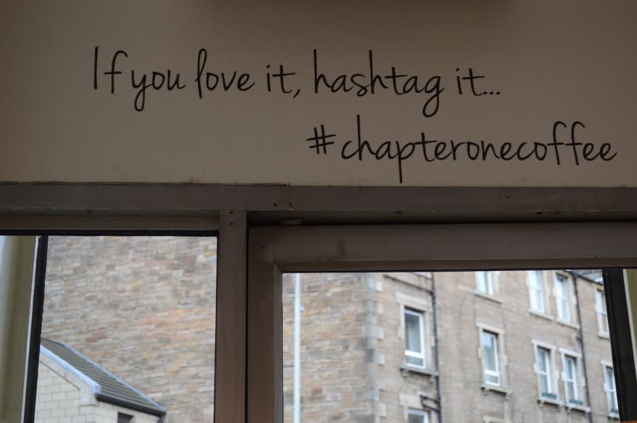 Text on the wall says If you love it, hashtag it... #chapteronecoffee