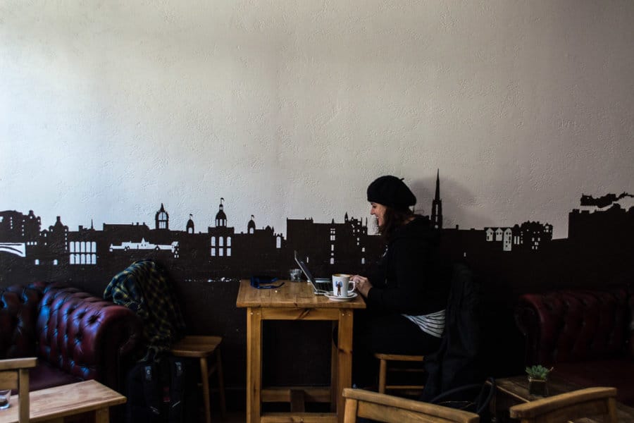 A woman works as a digital nomad at a cafe on her laptop.