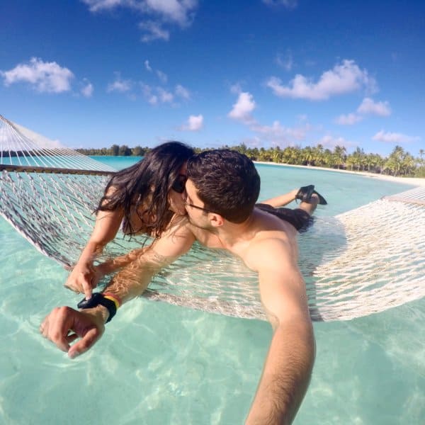 A couple kisses on a hammock over the water.