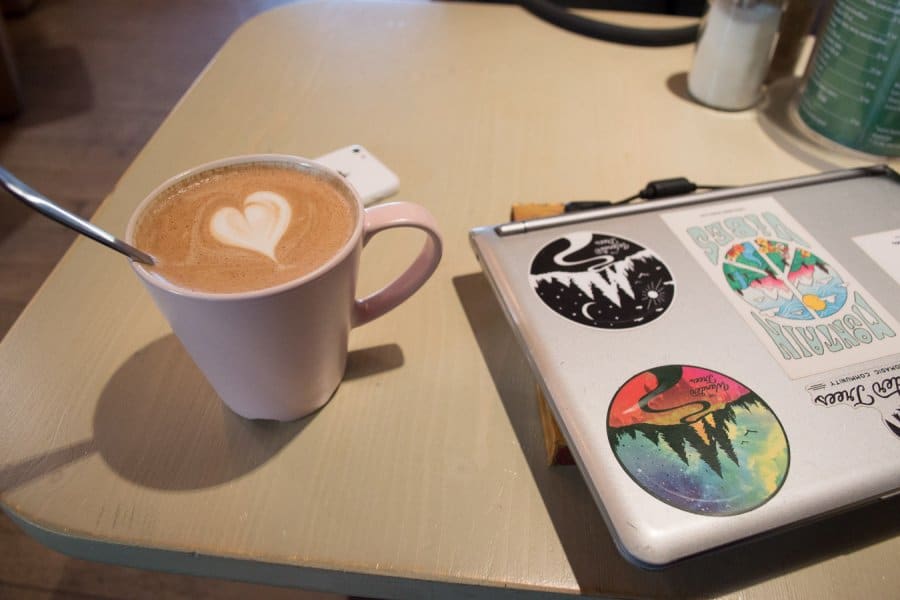 A cup of coffee on a table next to a closed laptop.