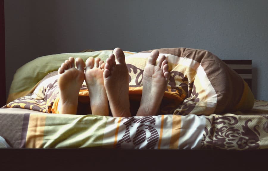 Photo of two people's feet at the end of a bed.