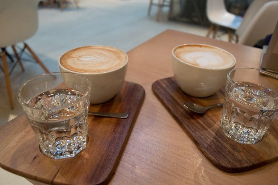 Cups of coffee and water on a wooden table.