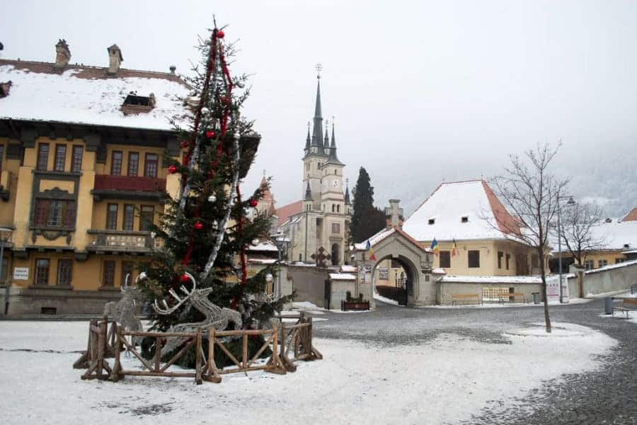 An empty plaza in snow with a Christmas tree set up in the middle.