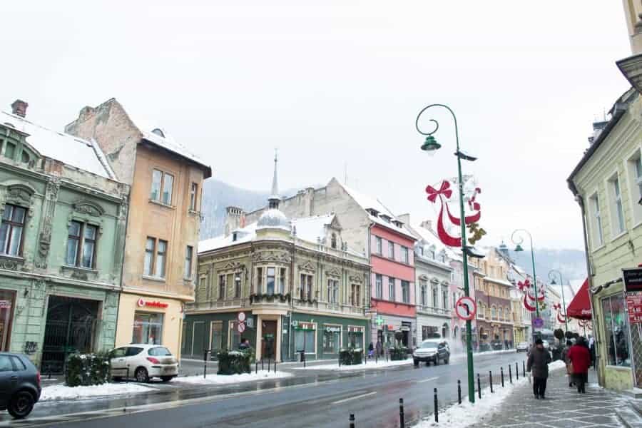 Cars parked along a street lined with colorful shops in winter.