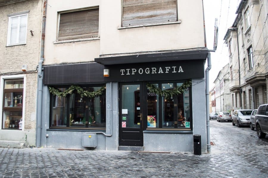 Exterior of a shop with a black awning that says Tipografia.
