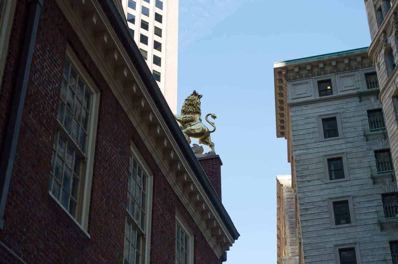 A statue of a golden lion on top of a brick building.